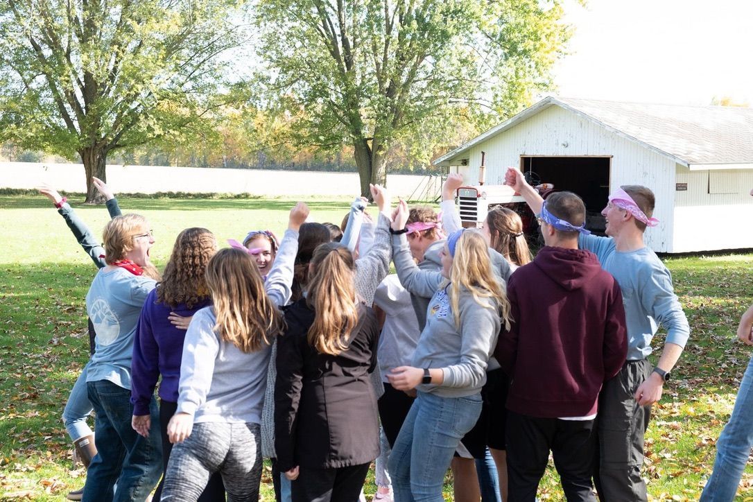 A group of people are standing in a circle with their arms in the air