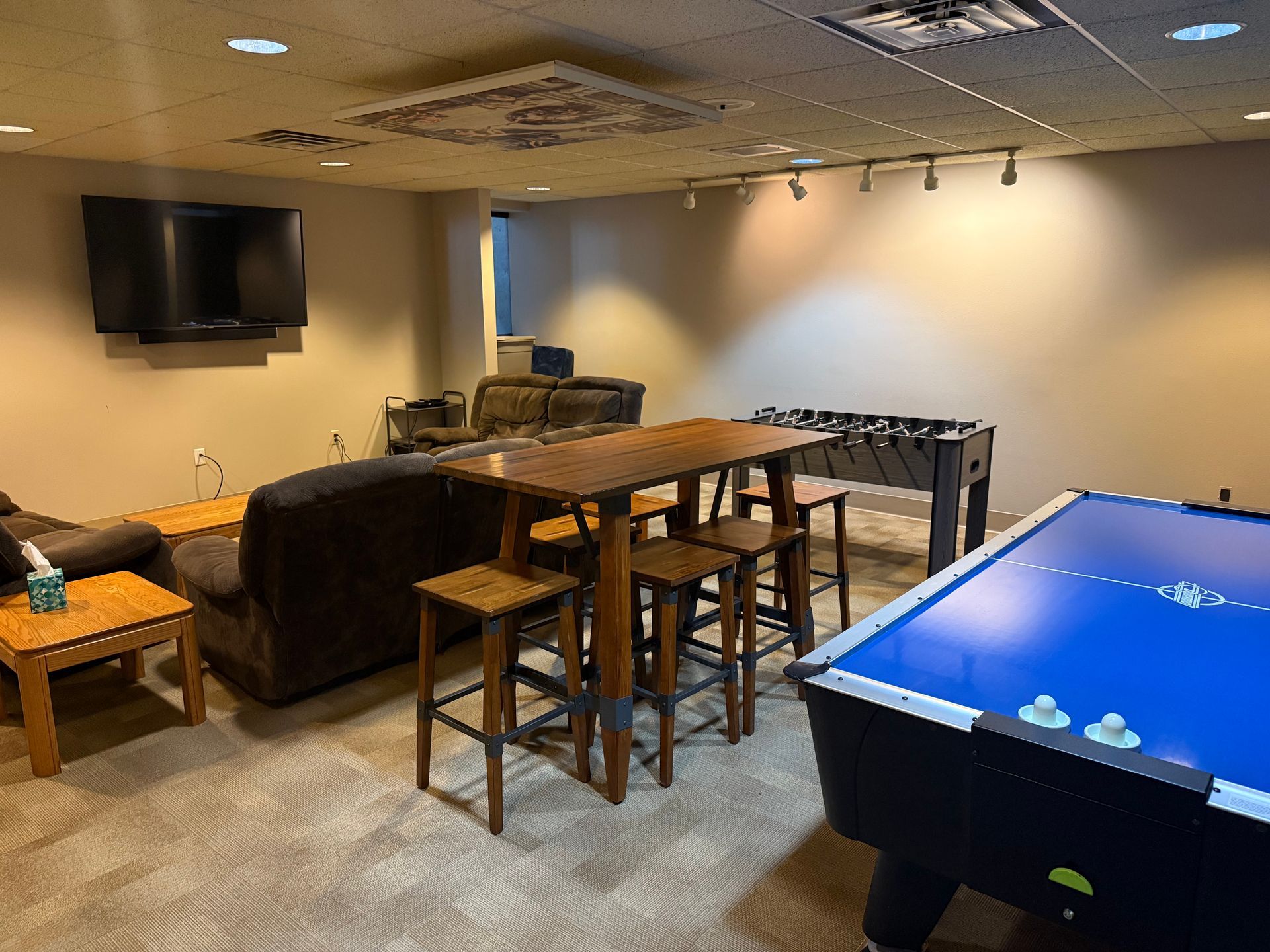 Game room with pool table, foosball, bar stools, TV, and seating.
