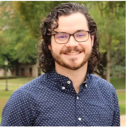 A man wearing glasses and a blue shirt is smiling for the camera.