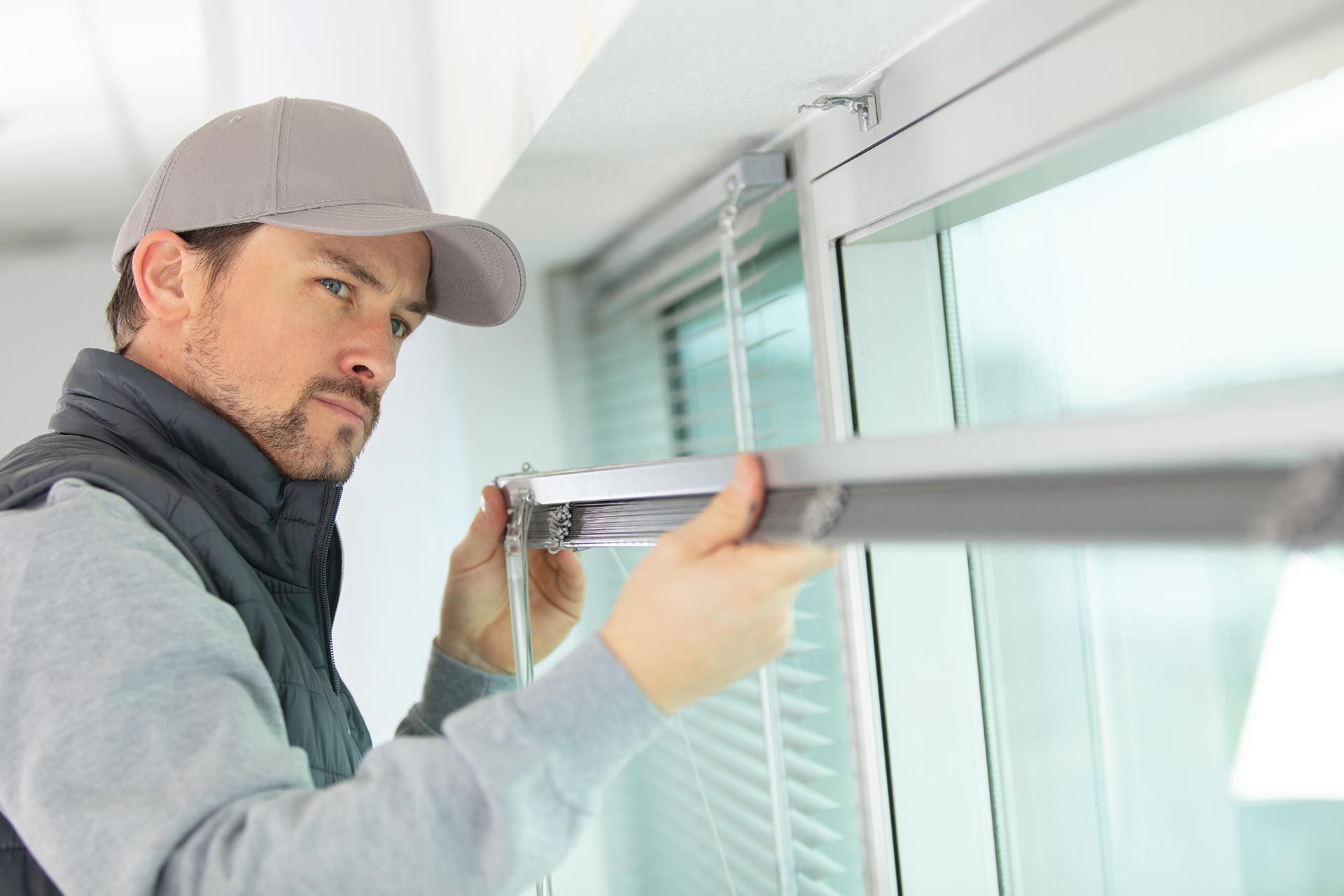 A man is installing a window blind.