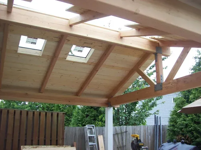 Wooden backyard roof with skylight windows and a ladder beneath it