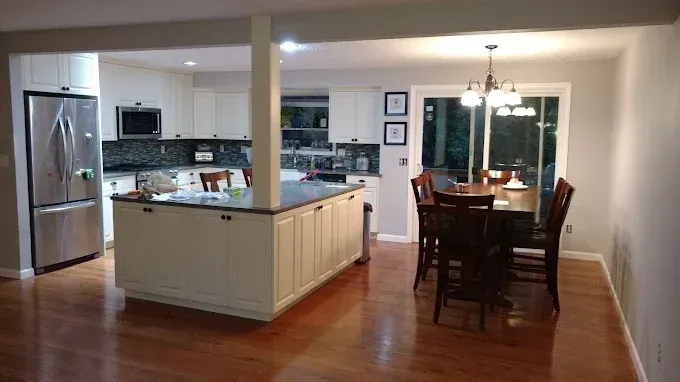 Open-concept kitchen and dining area with stainless steel appliances, white island, and dark wood floors