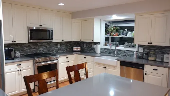 Modern kitchen with white cabinets, granite counters, stainless appliances, and a breakfast bar