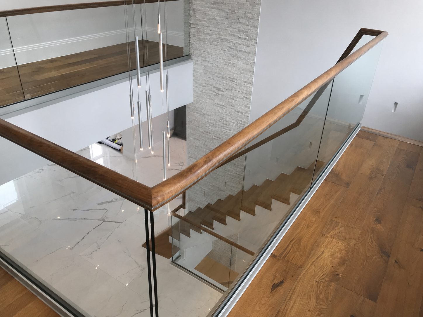 Contemporary staircase landing with glass balustrade and oak handrails