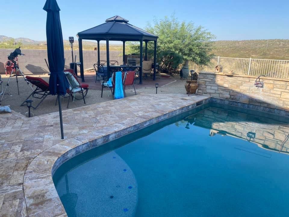 Backyard pool and patio with gazebo, lounge chairs, umbrella, and desert landscaping