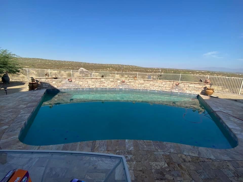 Outdoor stone pool with turquoise water under a clear blue sky, surrounded by a rocky landscape