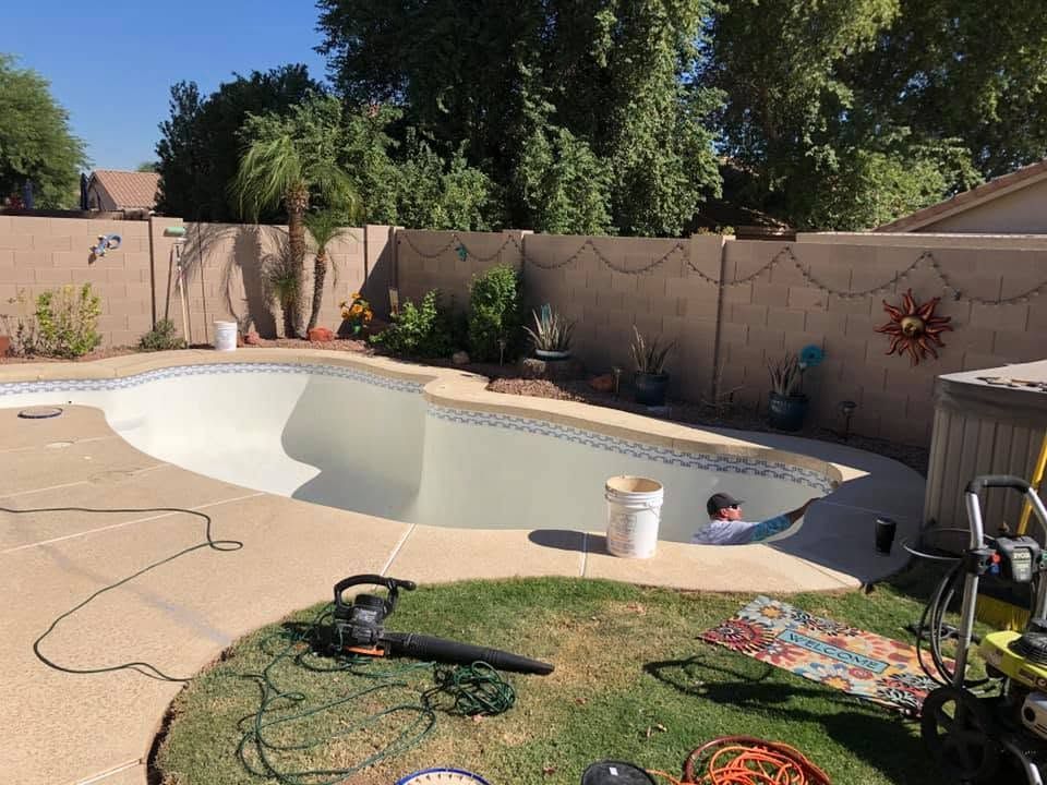 Backyard pool with a child in the shallow end, patio furniture, and a garden hose on the deck