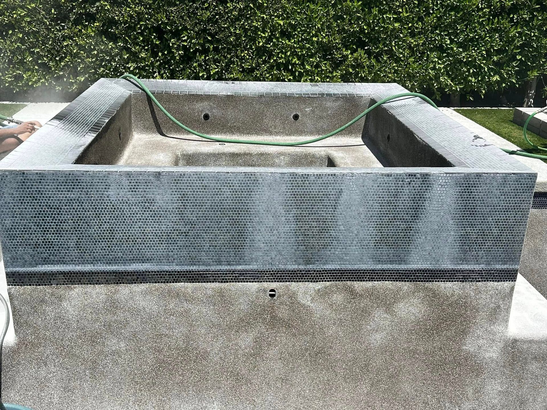 Empty stone water feature with a gray tiled rim in a garden courtyard