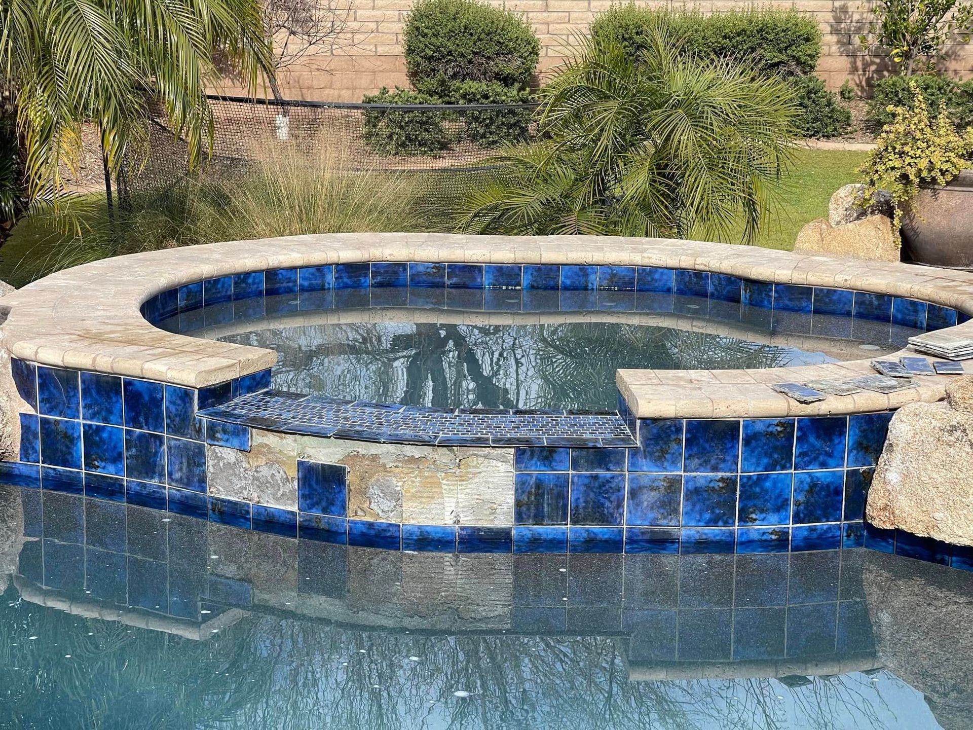 Round blue-tiled spa pool with bubbling water in a landscaped yard
