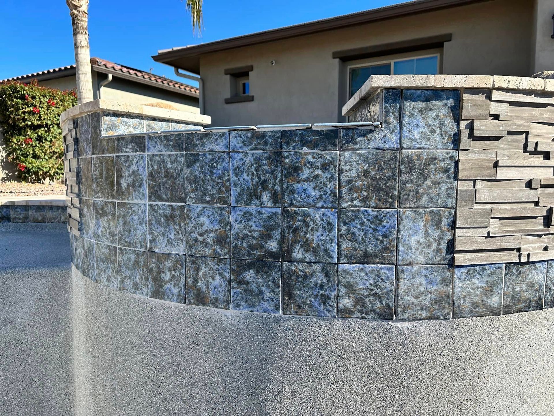 Stone-clad curved front wall outside a house, with stacked stone steps on the right