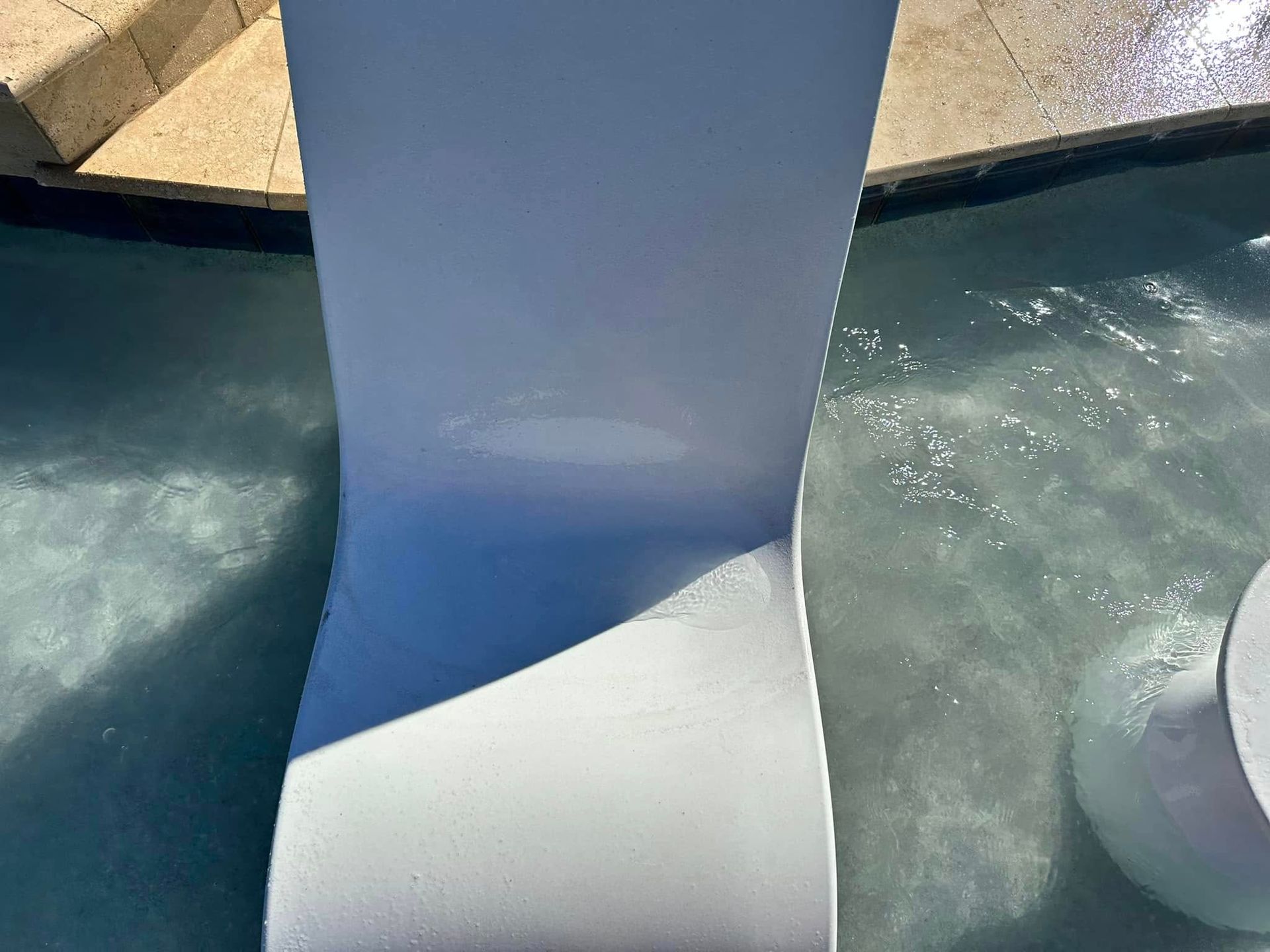 White sculpture or bench in shallow blue water with stone edging around it