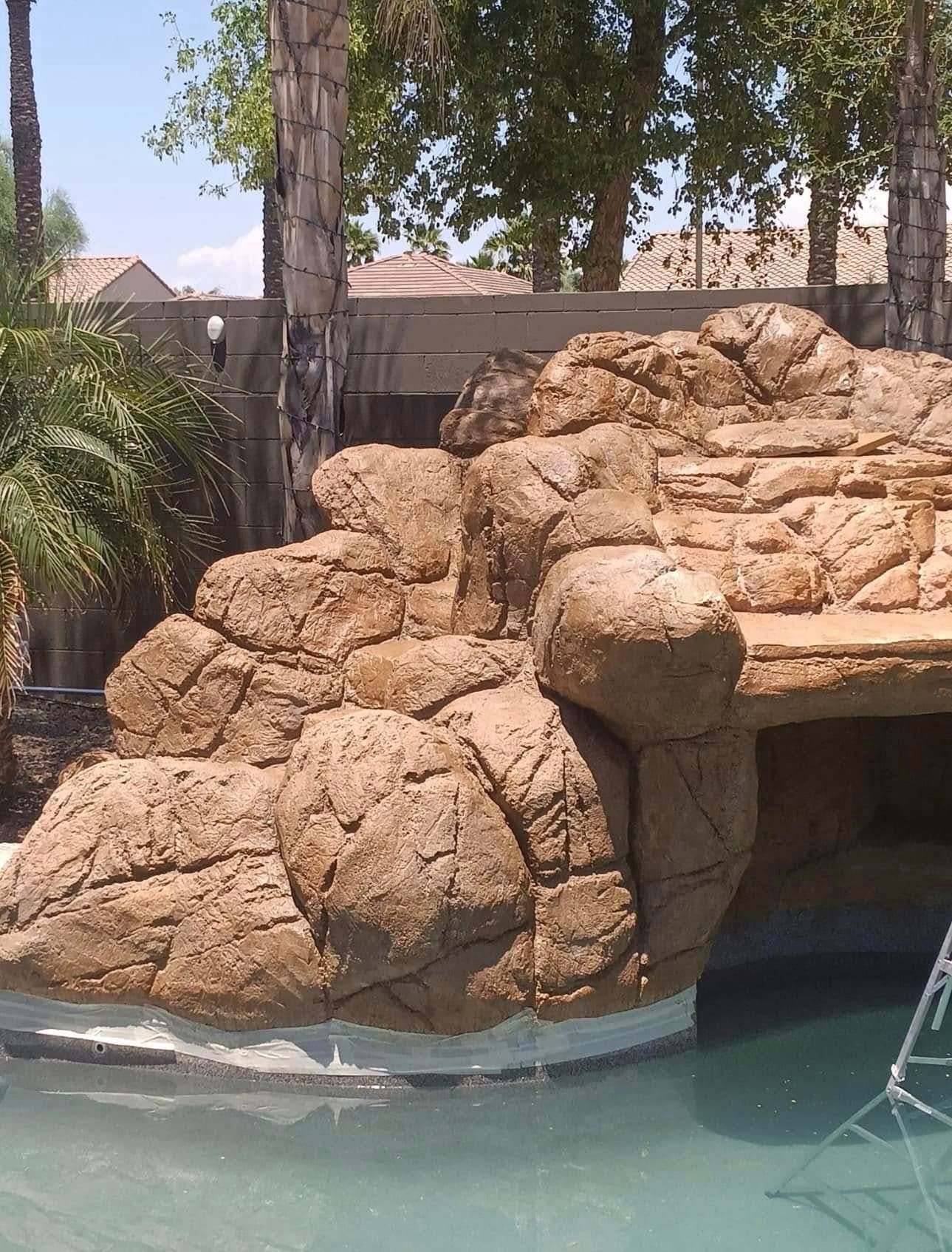 Rock formation beside a turquoise pool, with trees and a ladder in the background