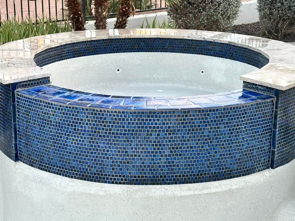 Blue-tiled circular fountain with a raised curved wall and empty white basin in a courtyard