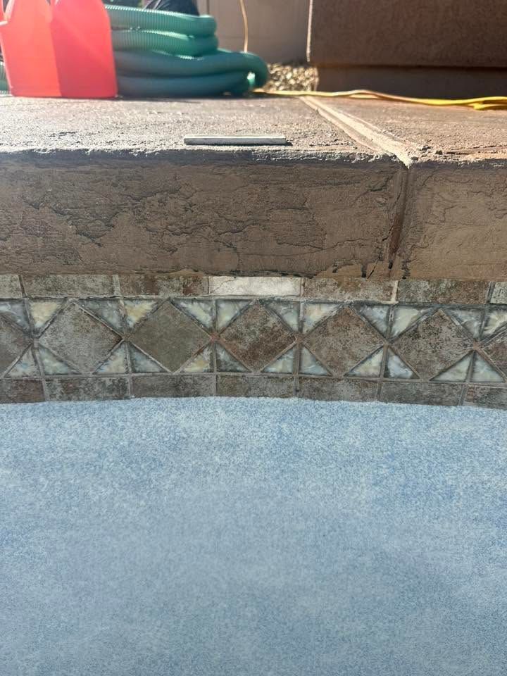 Concrete steps with a decorative tile border and a green hose on the top step.