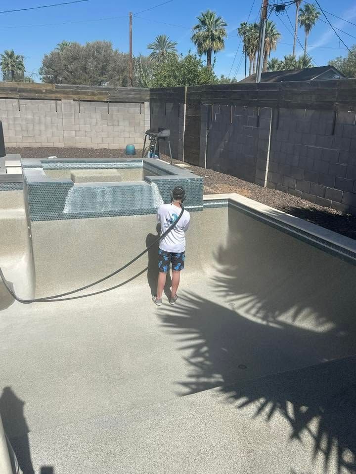Person holding a hose beside an empty backyard pool under bright sun
