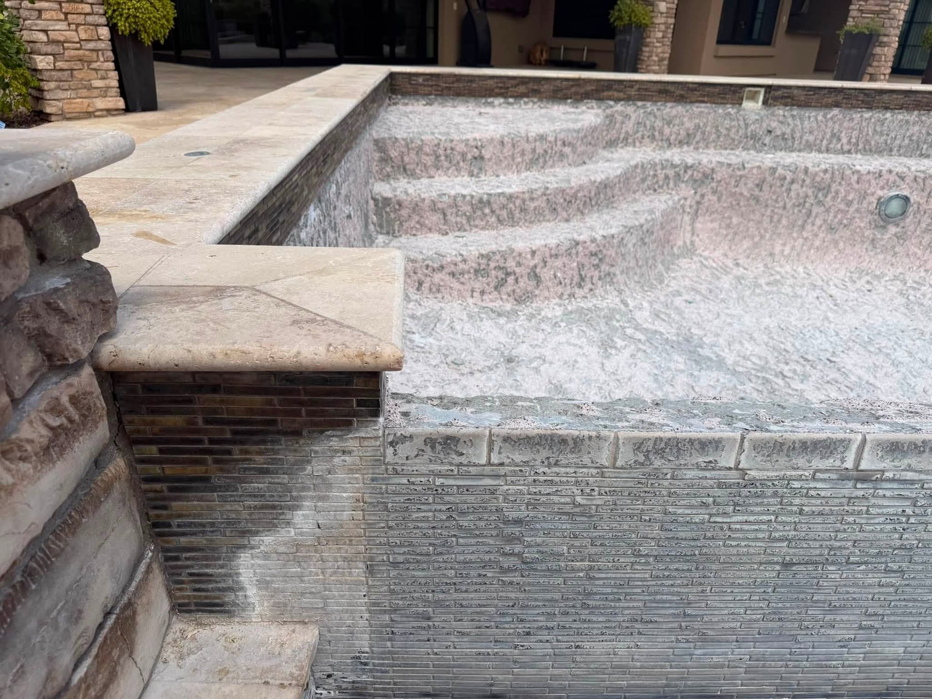 Empty stone-lined fountain with a shallow basin and tiled steps in a courtyard