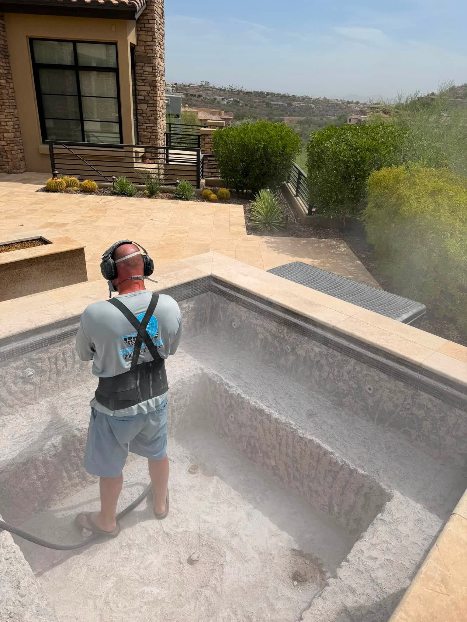 Person in a backyard pool being sprayed by water while wearing headphones and a harness at the pool edge
