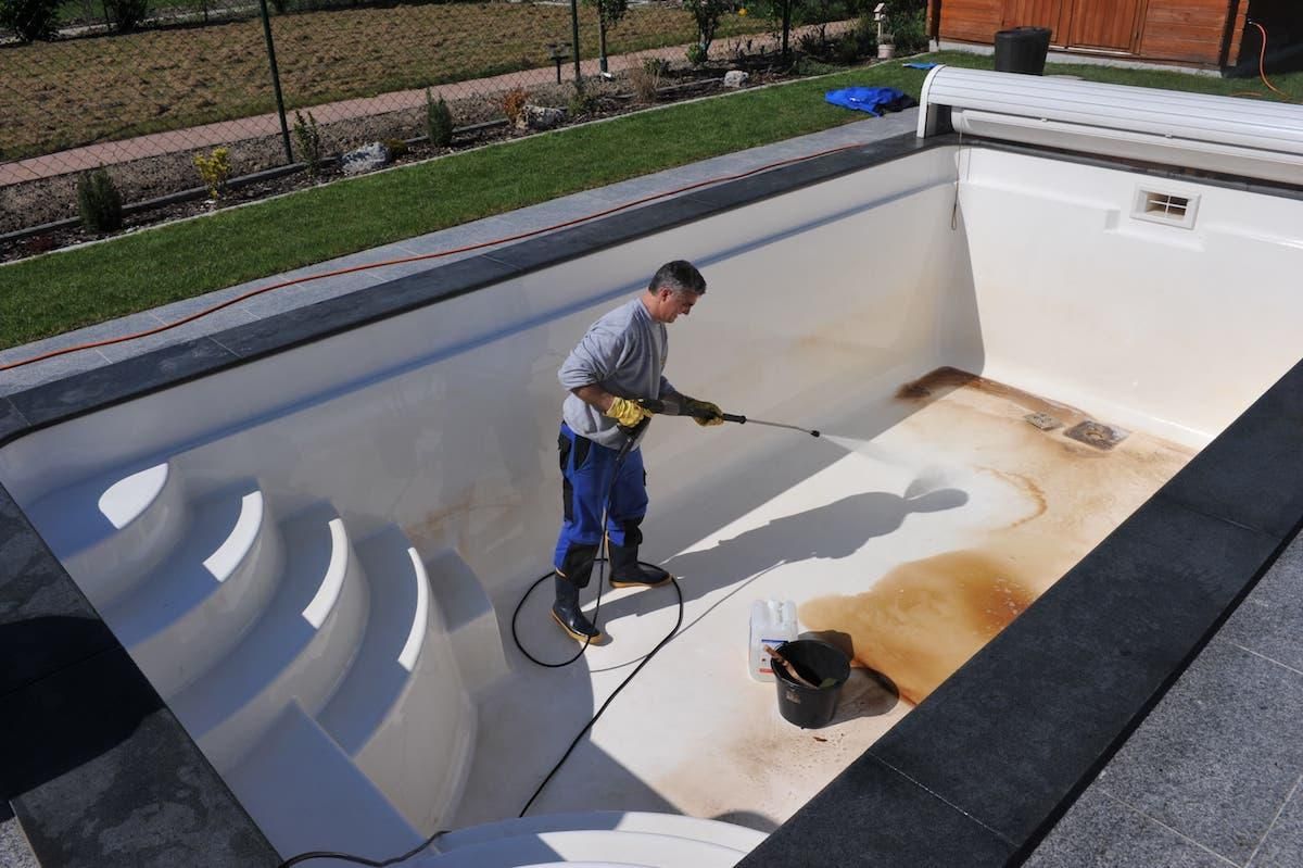 Wet concrete pouring from a truck chute onto a construction site, forming a gravelly slab surface