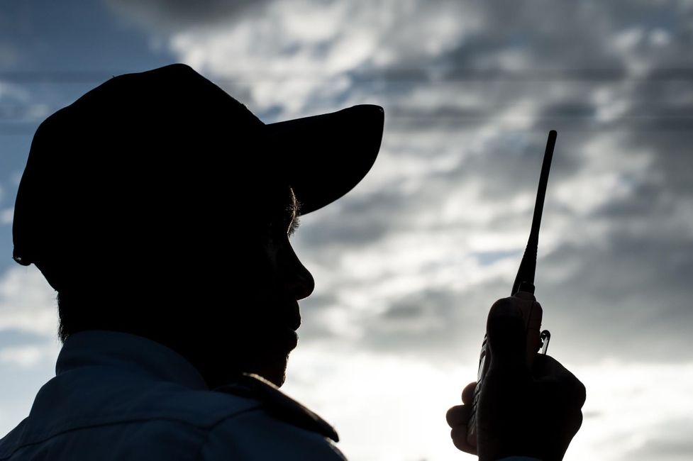 A silhouette of a man holding a walkie talkie against a cloudy sky