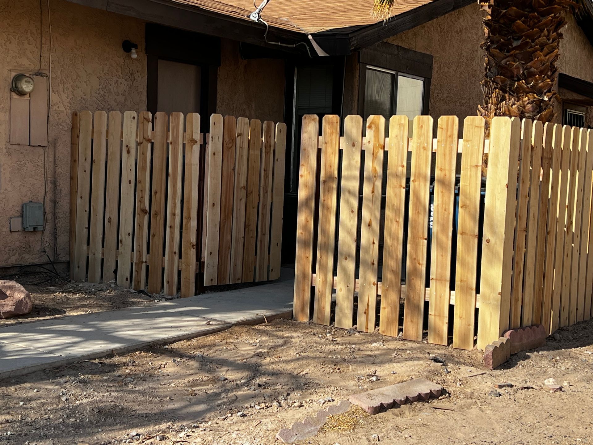 Person using a drill to attach a wooden picket to a fence.