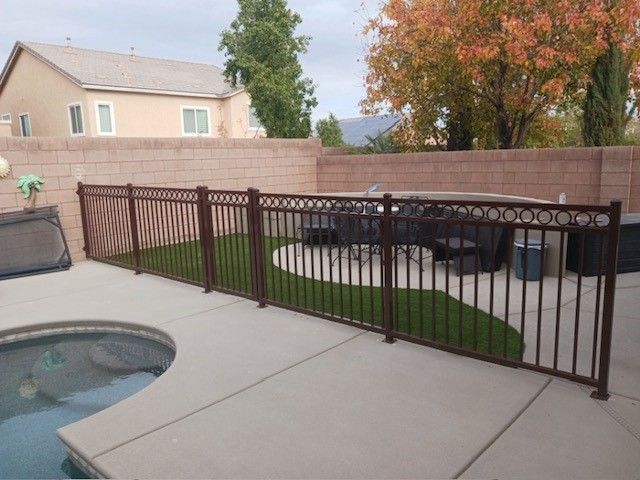 Close-up of a wrought-iron fence with gold-colored, twisted balusters against a blurred green background.