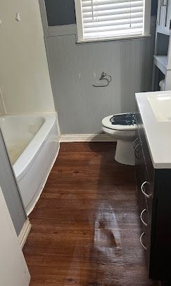 A bathroom with a toilet , sink , bathtub and window.