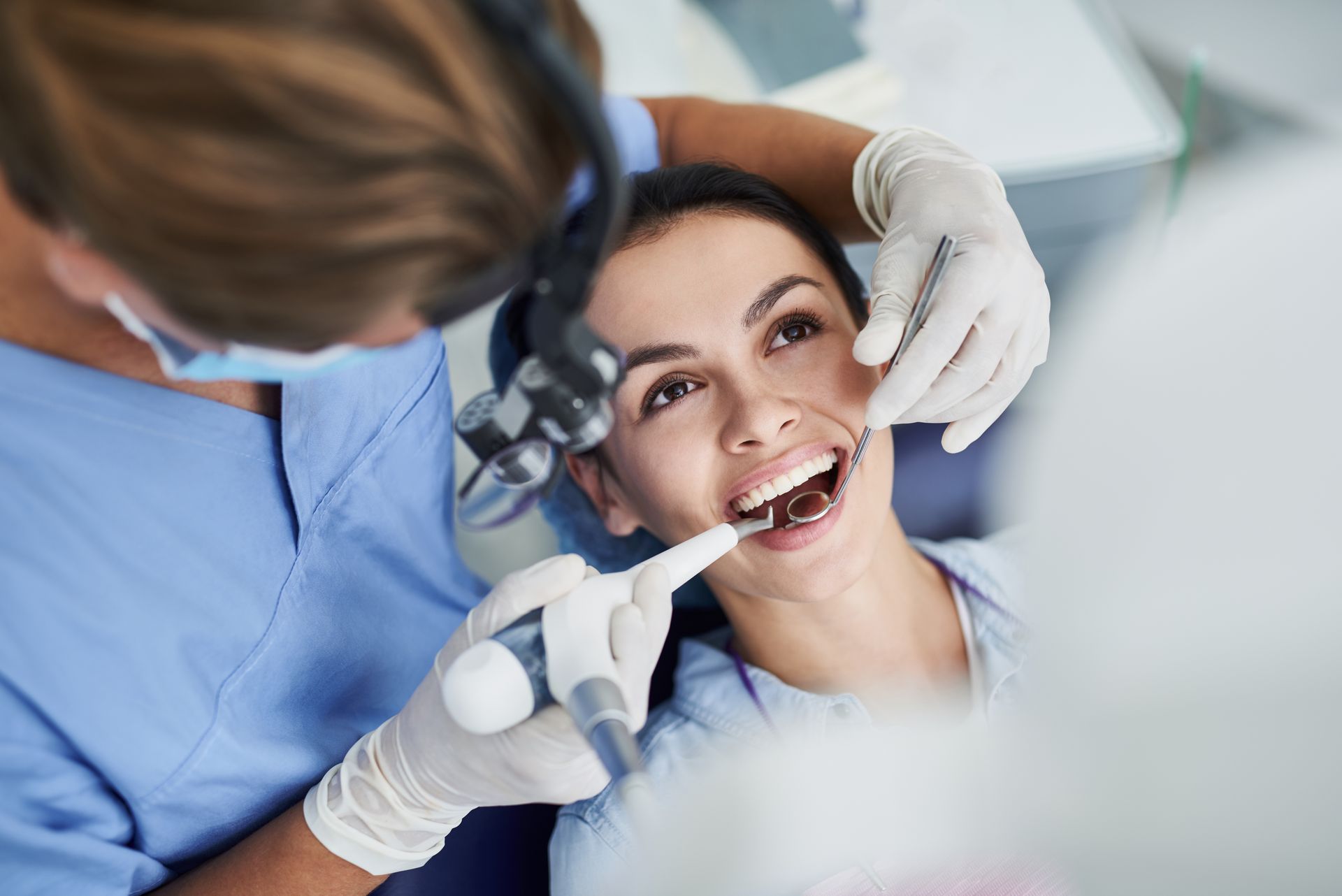 Patient receiving teeth whitening treatments at dental clinic with dentist using tools. Patient receiving teeth whitening treatments at dental clinic with dentist using tools.