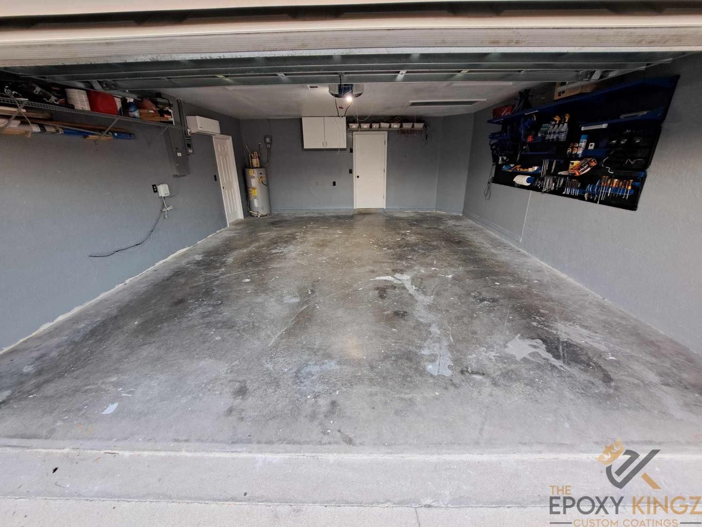 A professional using a concrete grinder to prepare a garage floor for epoxy flooring.
