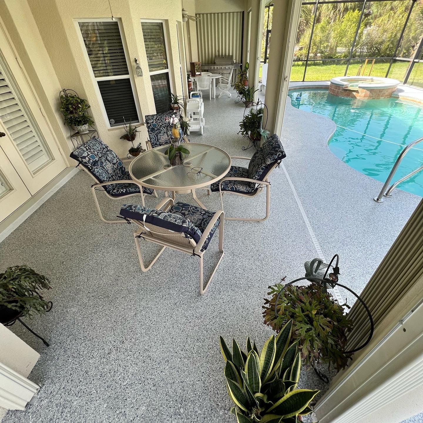 Patio with pool. Chairs, table, plants, and pool surround a covered outdoor space.