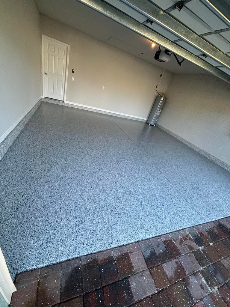 Garage with speckled gray epoxy flooring, door, and exposed garage door mechanism.