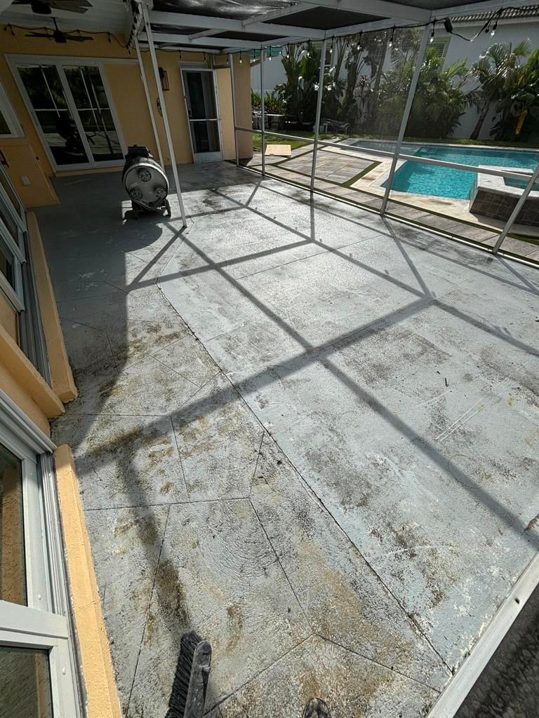Concrete patio with a pool in the background, under a screen enclosure.