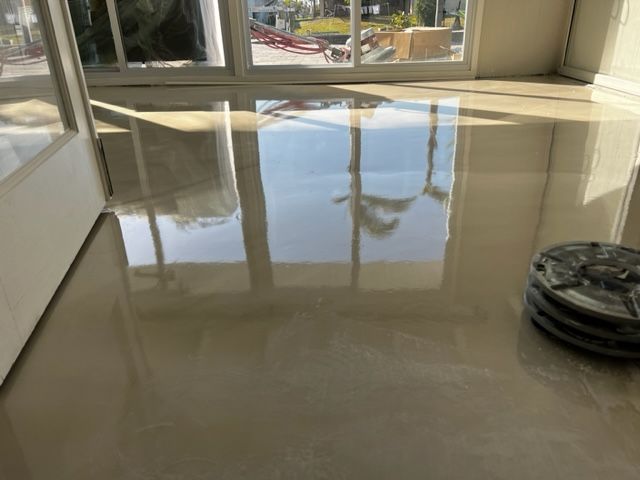 Shiny, polished light gray flooring with reflections of windows, natural light.