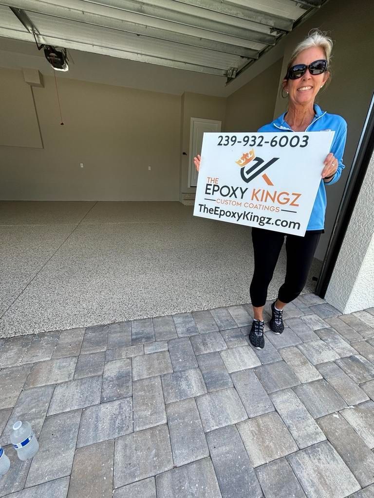 Woman holding Epoxy Kingz sign in a garage with a speckled epoxy floor.