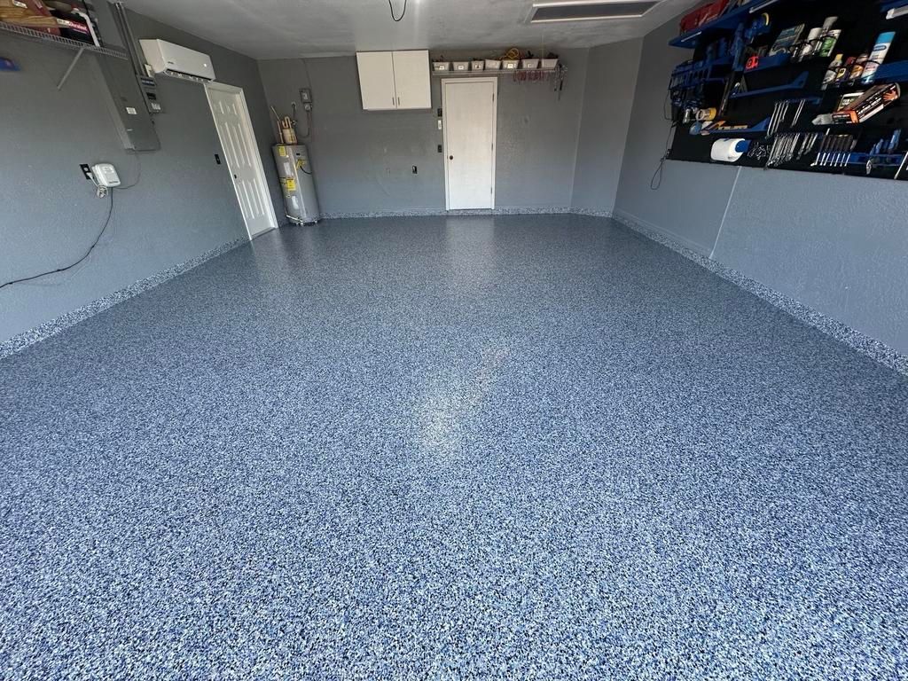 Garage with a blue and gray speckled epoxy floor. Walls are gray, and a white door is visible.