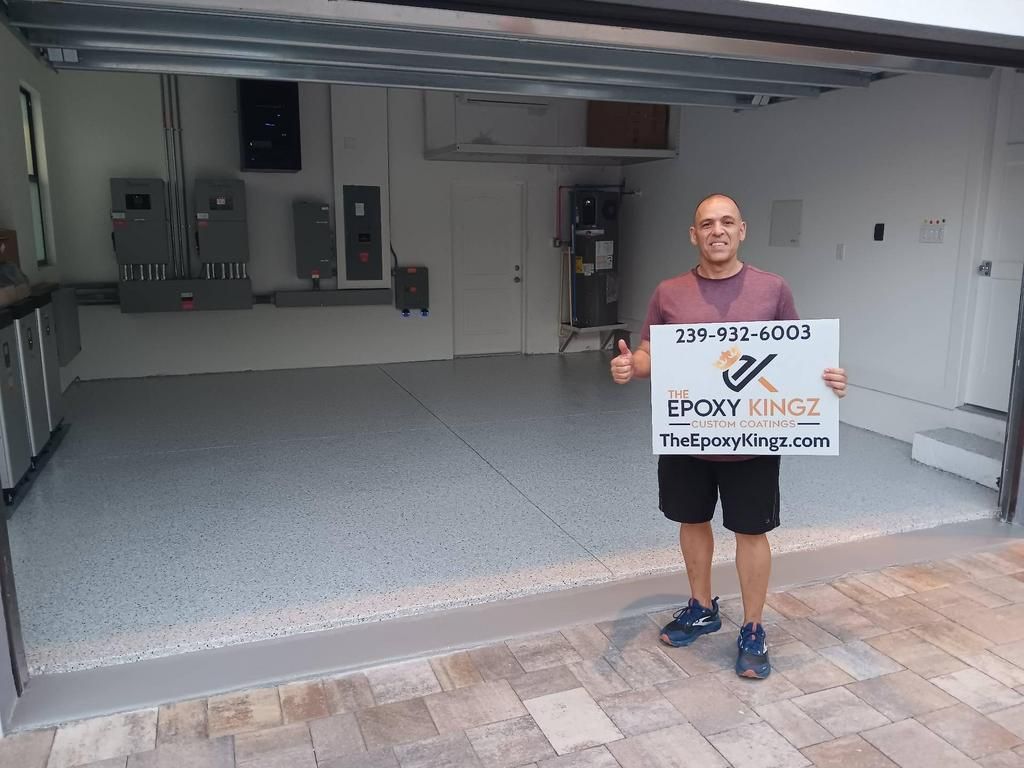 Man stands in a newly coated garage holding a sign for 