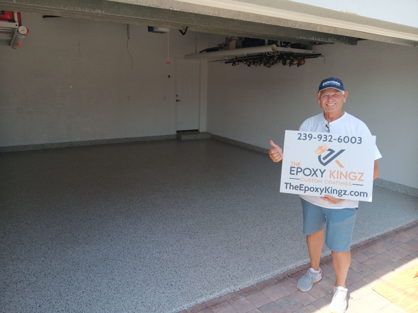 Man in garage with epoxy floor, holding sign for 