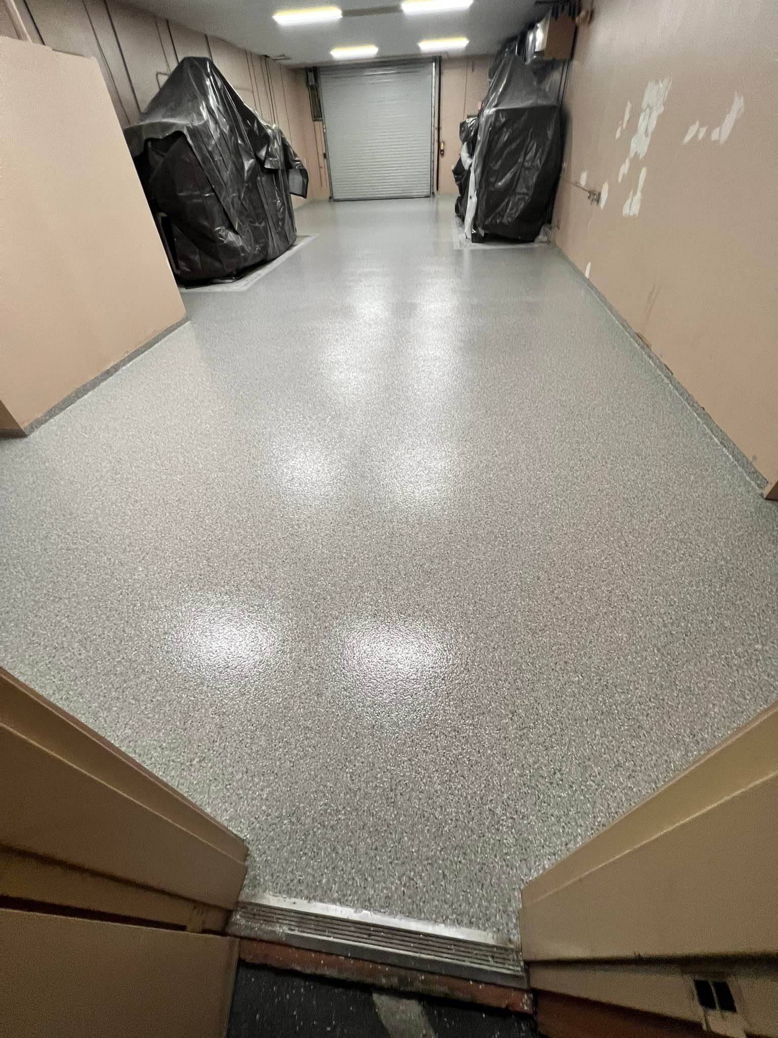 A professional using a squeegee to apply an epoxy coating to a garage floor.