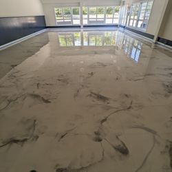 Shiny, marbled epoxy floor reflecting windows and interior. Light beige and gray tones.