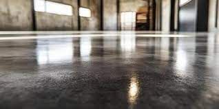 Reflective concrete floor in an industrial-looking room, with bright light reflecting from windows.