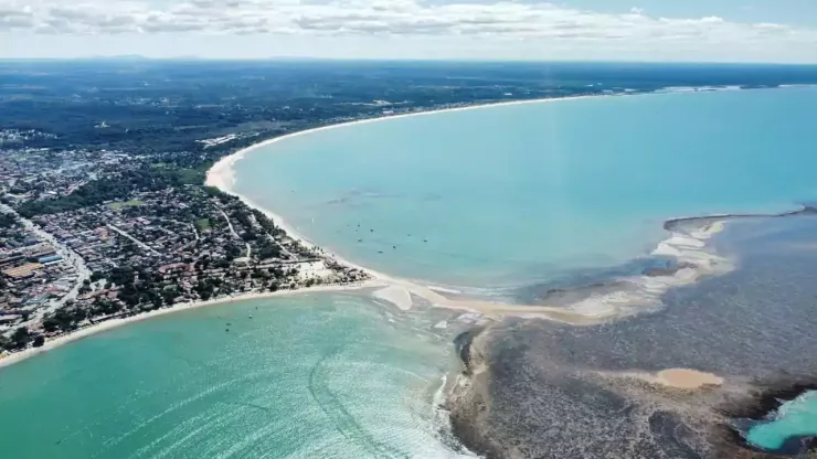 Uma vista aérea de um grande corpo de água com uma cidade ao fundo Areia do Atlântico Hotel