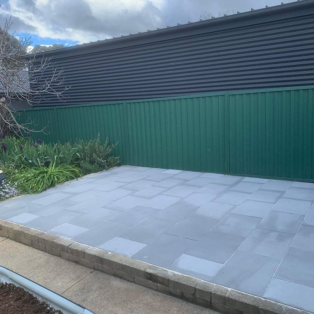 Gray Paved Patio With Green Corrugated Fence, and Black Wall — CLF Landscapes in Belconnen, ACT