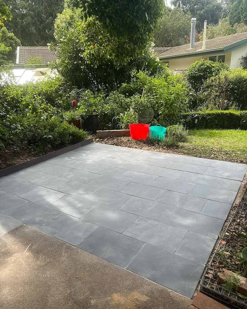 Patio With Dark Gray Tiles, Green Plants, Red and Turquoise Pots — CLF Landscapes in Belconnen, ACT