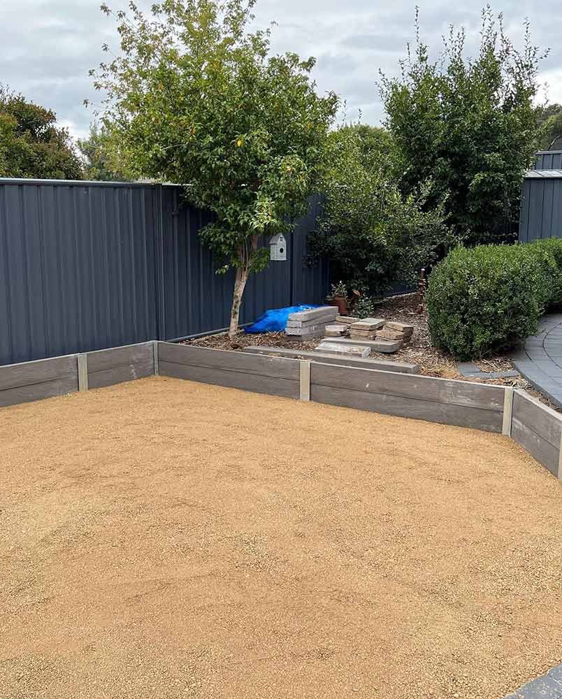 A Gravel Yard Bordered by a Retaining Wall, With a Fence and Trees in the Background — CLF Landscapes in Gungahlin, ACT