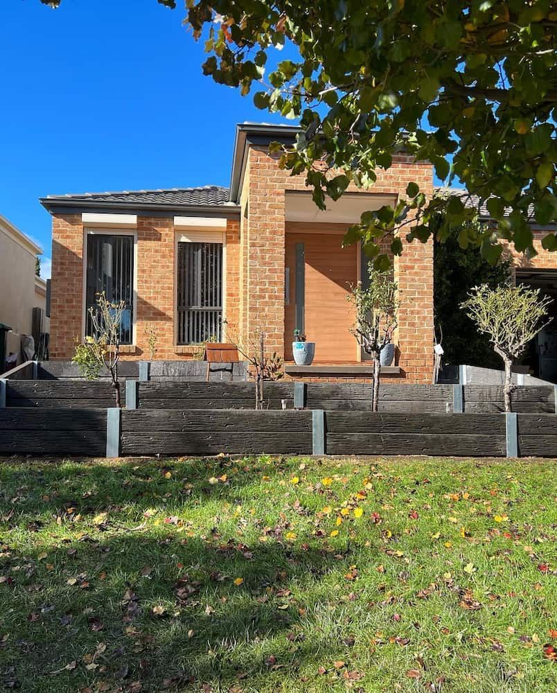 A Brick House With a Wooden Fence in Front of It — CLF Landscaping In Hawker, ACT