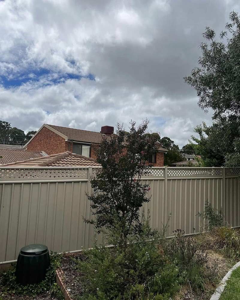 Backyard Scene With Fence, Brick House, Cloudy Sky, and Dark-leaved Tree — CLF Landscapes in Queanbeyan, NSW