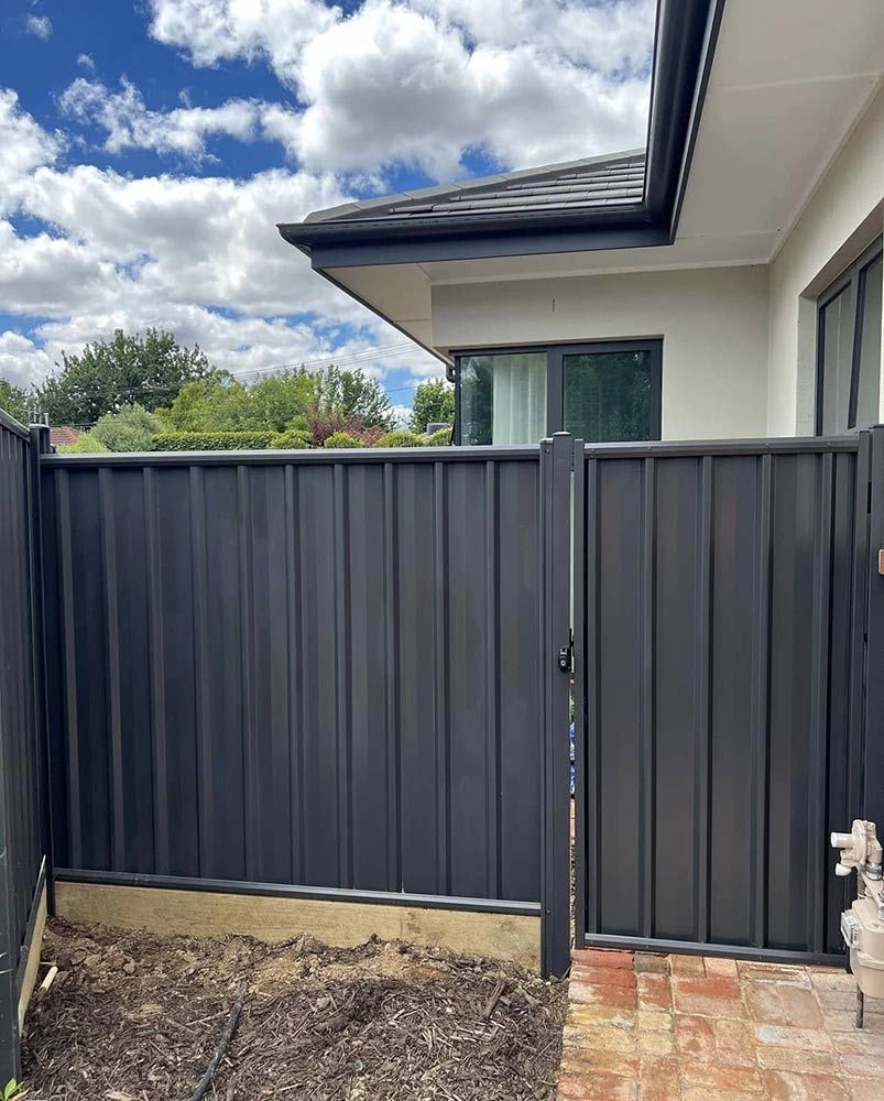 Black Metal Fence With a Gate Next to a Cream-coloured Building — CLF Landscapes in Tuggeranong, ACT