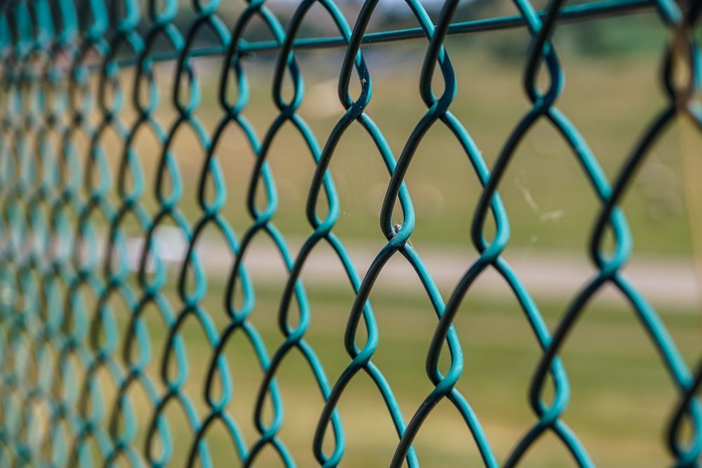 A Close Up of a Chain Link Fence With a Field in the Background — CLF Landscaping In Hawker, ACT