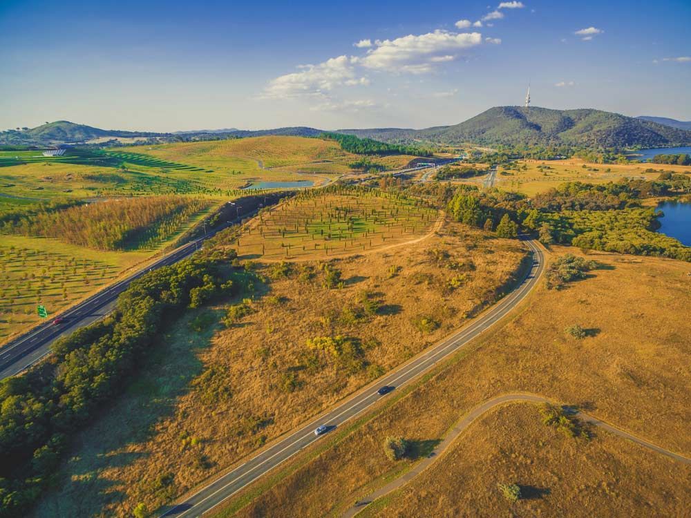 Aerial View of Roads Winding Through Golden Fields, With a Mountain in the Background — CLF Landscapes in Tuggeranong, ACT