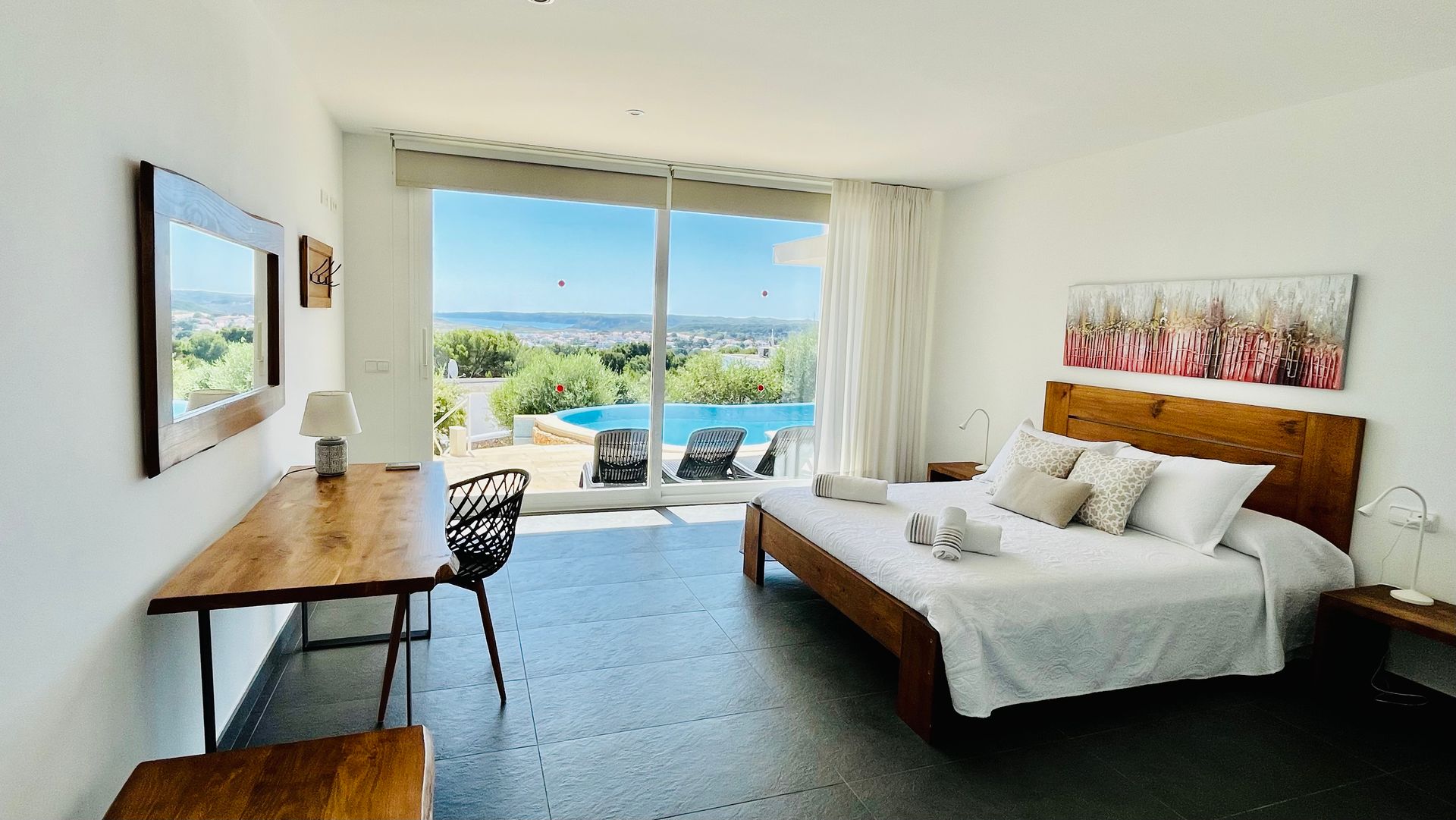 Dormitorio con cama, escritorio, gran ventanal con vista a la piscina y al paisaje.