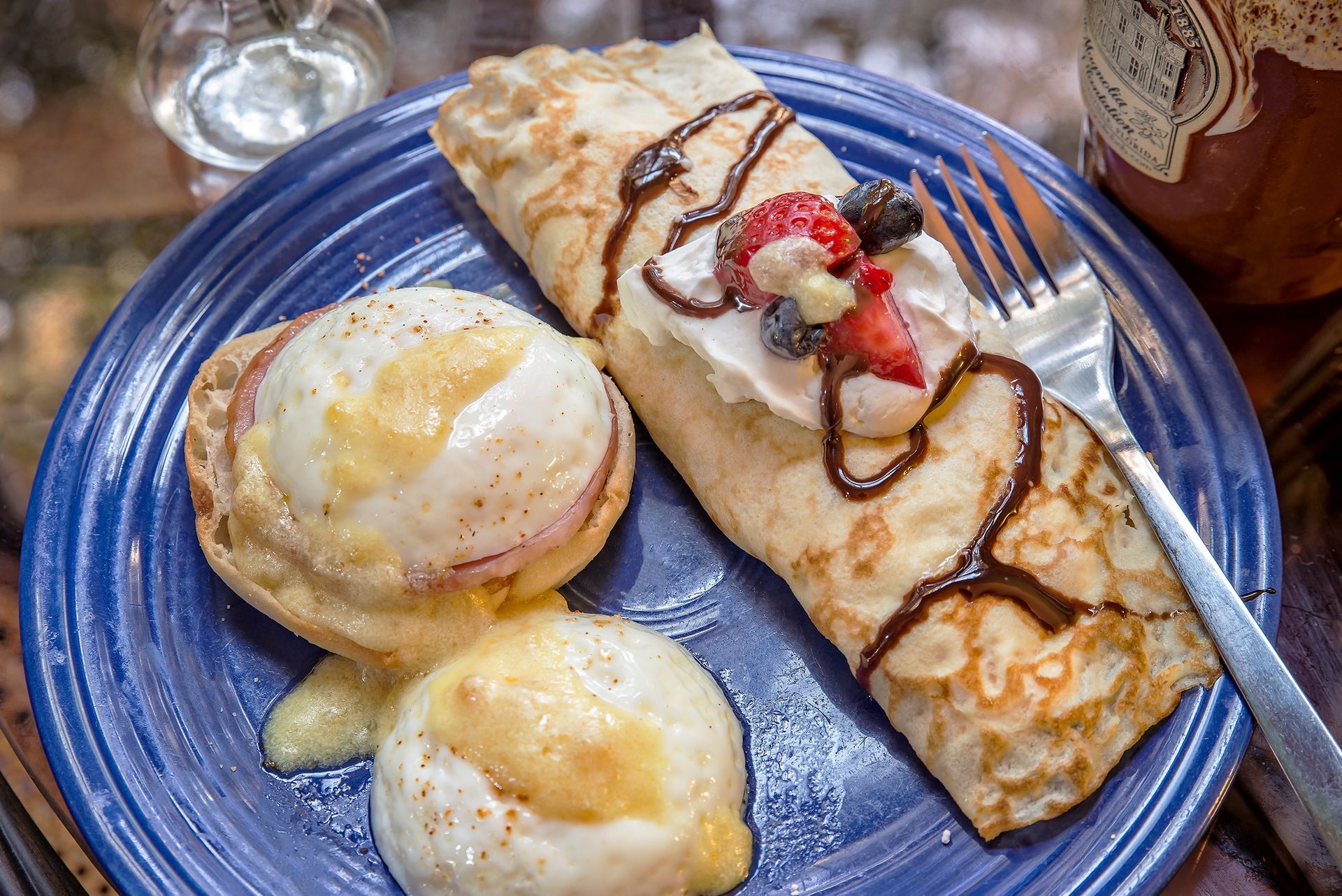 a blue plate topped with a crepe , eggs , and fruit .